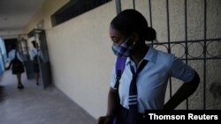 A pupil wearing a face mask to prevent the spread of the coronavirus disease (COVID-19), waits outside a schoolroom for the start of the lessons during the first day of school, at Lycee National de Petion Ville, in Port au Prince, Aug. 10, 2020.