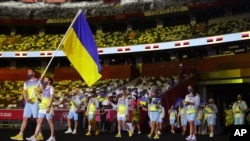 Olena Kostevych and Bogdan Nikishin, of Ukraine, carry their country's flag during the opening ceremony in the Olympic Stadium at the 2020 Summer Olympics, July 23, 2021, in Tokyo, Japan.