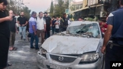 FILE - Emergency service personnel and residents gather at the site of an Israeli strike in Syria's capital Damascus, Oct. 2, 2024. Despite periodic strikes launched by Israel against targets inside Syria, the Syrian government has only condemned the strikes and taken no action.