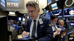 Para pialang saham bekerja di New York Stock Exchange (NYSE), Jumat (18/3).