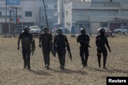 Riot police officers walk after dispersing a small protest against the postponement of the February 25 presidential election, in Parcelle, district of Dakar, Senegal, Feb. 16, 2024.