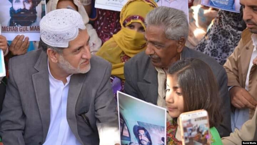 په دې تصویر کې اختر مېنګل او د وایس فار مېسېنګ بلوڅ تنظیم مشر قدیر بلوڅ په یوه مظاهره کې ناست لیدل کېږي