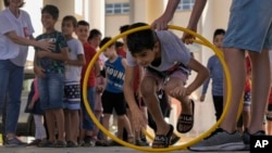 A volunteer of the Russian Cultural Center entertains displaced children at a school in Beirut, Oct. 3, 2024, after fleeing the Israeli airstrikes in the south.