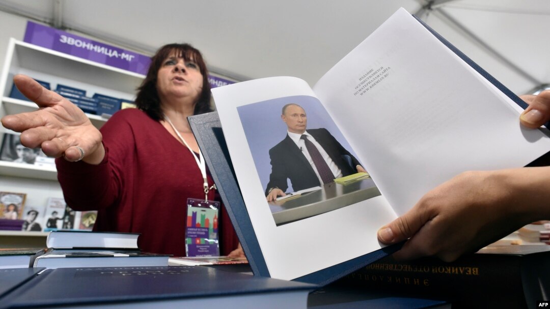 A customer holds a copy of Russian President Vladimir Putin's book "Direct speech" as she speaks with a vendor (L) at the Red Square Book Festival in Moscow on June 3, 2016.