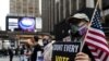 FILE - A man wearing a protective mask due to COVID-19 pandemic holds a sign outside Madison Square Garden, which is used as a polling station, on the first day of early voting in Manhattan, New York, Oct. 24, 2020. 