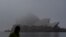 A man wearing a protective face mask walks past the Sydney Opera House, seen shrouded in fog, in Sydney, Australia, July 1, 2021.