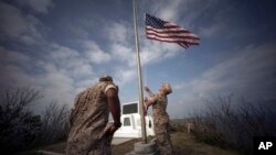 Marinir-marinir AS mengibarkan bendera Amerika di puncak Gunung Suribachi, dekat lokasi upacara peringatan 70 tahun Pertempuran Iwo Jima, atau Ioto, Jepang (21/3). (AP/Eugene Hoshiko)