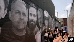 FILE - People gather in an alley emblazoned with a mural depicting American hostages and wrongful detainees who are being held abroad, July 20, 2022, in the Georgetown neighborhood of Washington. March 9, 2024, marks the nation's first U.S. Hostage and Wrongful Detainee Day.