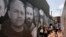 FILE - People gather in an alley emblazoned with a mural depicting American hostages and wrongful detainees who are being held abroad, July 20, 2022, in the Georgetown neighborhood of Washington. March 9, 2024, marks the nation's first U.S. Hostage and Wrongful Detainee Day.