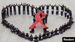 Students make a formation in the shape of a heart and a red ribbon during a HIV/AIDS awareness campaign.