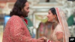 อนันต์ อัมบานี (ซ้าย) ขณะจับมือกับราดิก้า เมอร์ชานต์ (ขวา) ในพิธีมงคลสมรสของทั้งสองในนครมุมไบ ประเทศอินเดีย วันที่ 12 กรกฎาคม 2024 (ที่มา: Reliance Industries via AP)