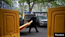 Seorang pekerja mengenakan masker wajah menyingkirkan penghalang di sebuah jalan di Wuhan, pusat wabah virus corona (COVID-19) di Wuhan, 5 April 2020. (Foto: Reuters)