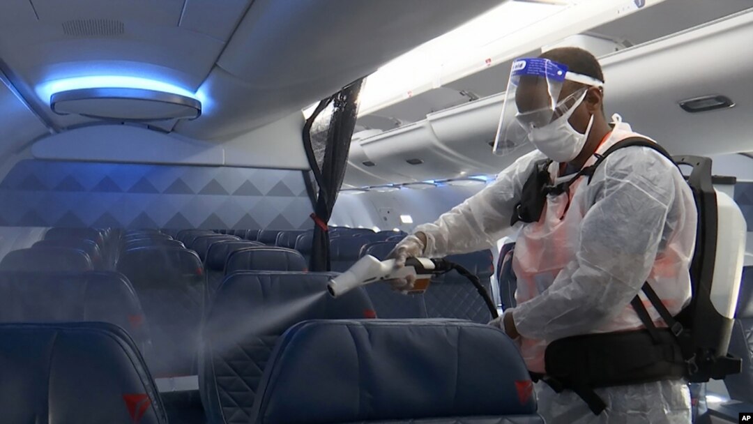 Melaku Gebermariam tampak menyemprotkan cairan disinfektan ke arah kursi-kursi di pesawat Delta Airplane, yang tengah berada di Bandara Reagan Washington di Arlington, Virginia, pada 22 Juli 22 2020. (Foto: AP/Nathan Ellgren)