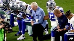 The Dallas Cowboys, led by owner Jerry Jones, center, take a knee during the national anthem prior to an NFL football game against the Arizona Cardinals, in Glendale, Arizona, Sept. 25, 2017.