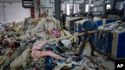 A worker feeds discarded textiles to a shredding machine at the Wenzhou Tiancheng Textile Company, one of China's largest cotton recycling plants in Wenzhou, Zhejiang province on March 20, 2024. The factory repurposes discarded cotton clothes.