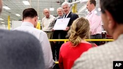 Republican presidential hopeful, former House Speaker Newt Gingrich, center, prepares to sign the Strong America Now pledge, while touring C&M Machine Products in Hudson, New Hampshire, June 8, 2011.