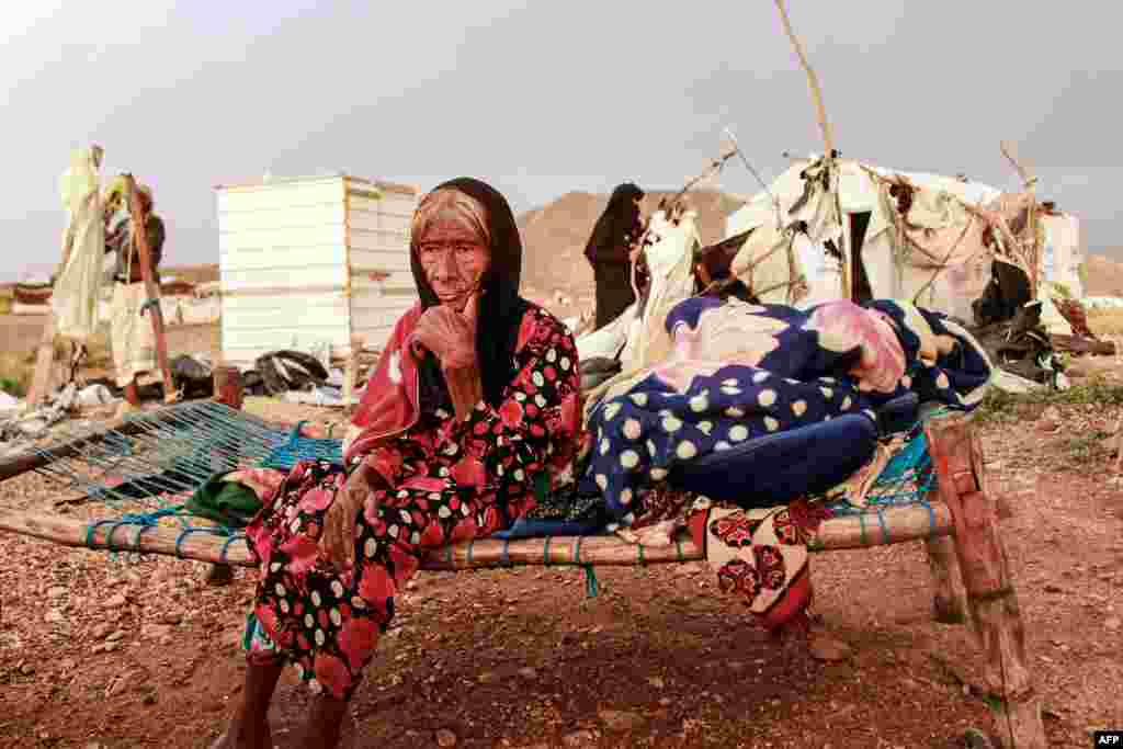 An elderly woman sits on a makeshift bed as people try to salvage tents damaged by torrential rain, at a camp for Yemenis displaced by conflict in the northern Hajjah province, Sept. 30, 2020.
