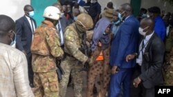 Le personnel de sécurité escorte un agresseur présumé du président malien, le colonel Assimi Goita, hors de la grande mosquée Fayçal à Bamako, le 20 juillet 2021.