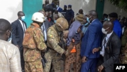 FILE - Security personnel escort an alleged attacker (C) from The Grand Fayçal Mosque in Bamako, July 20, 2021, after two assailants attempted to stab Mali's interim President Assimi Goita.