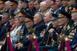 FILE - Russian President Vladimir Putin, center right, and Kazakhstan's former president Nursultan Nazarbayev, center left, attend the Victory Day military parade to mark 74 years since the end of World War II, in Red Square in Moscow, May 9, 2019.
