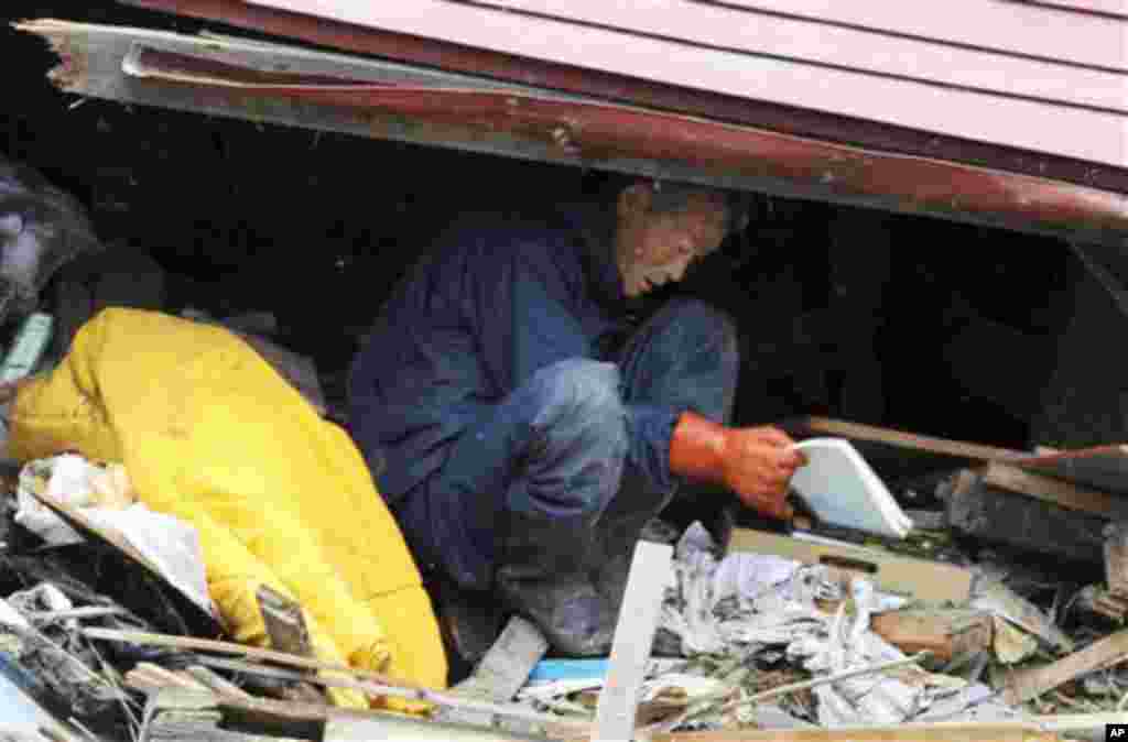 A man tries to take his belongings from his damaged home in Miyako. (AP Image)