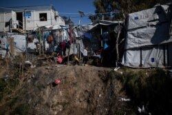 Children play next to the fence of the Moria migrant camp on the island of Lesbos, Greece, Feb. 18, 2020.