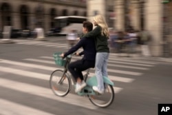 Youths ride on a bicycle in Paris, Wednesday, Sept. 13, 2023. (AP Photo/John Leicester)