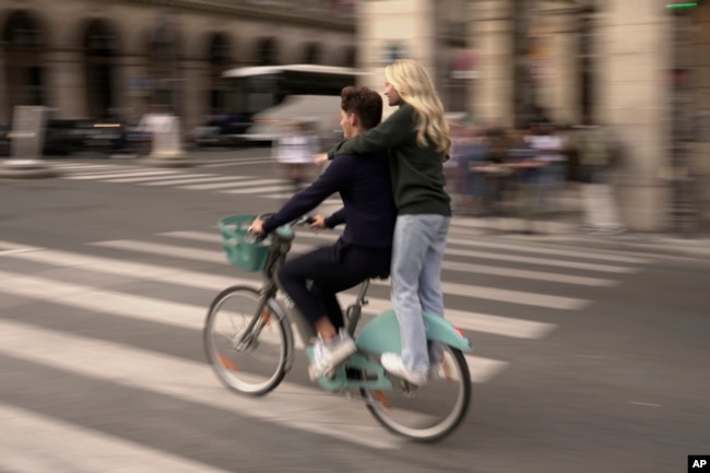 Youths ride on a bicycle in Paris, Wednesday, Sept. 13, 2023. (AP Photo/John Leicester)