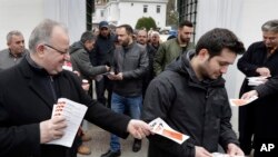 Mantan ketua komunitas Turki di Jerman, Kenan Kolat, kiri, membagikan brosur referendum kepada seorang pria yang memegang brosur pro-referendum setelah sholat Jumat di masjid Sehitlik di Berlin, Jerman, Jumat, 17 Maret 2017. Turki akan mengadakan referendum nasional pada 16 April untuk melebarkan kekuasaan Presiden Turki Recep Tayyip Erdogan. (AP Photo/Michael Sohn)