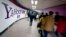 FILE - Chinese subway riders walk past a Yahoo advertisement at a metro station in Beijing.