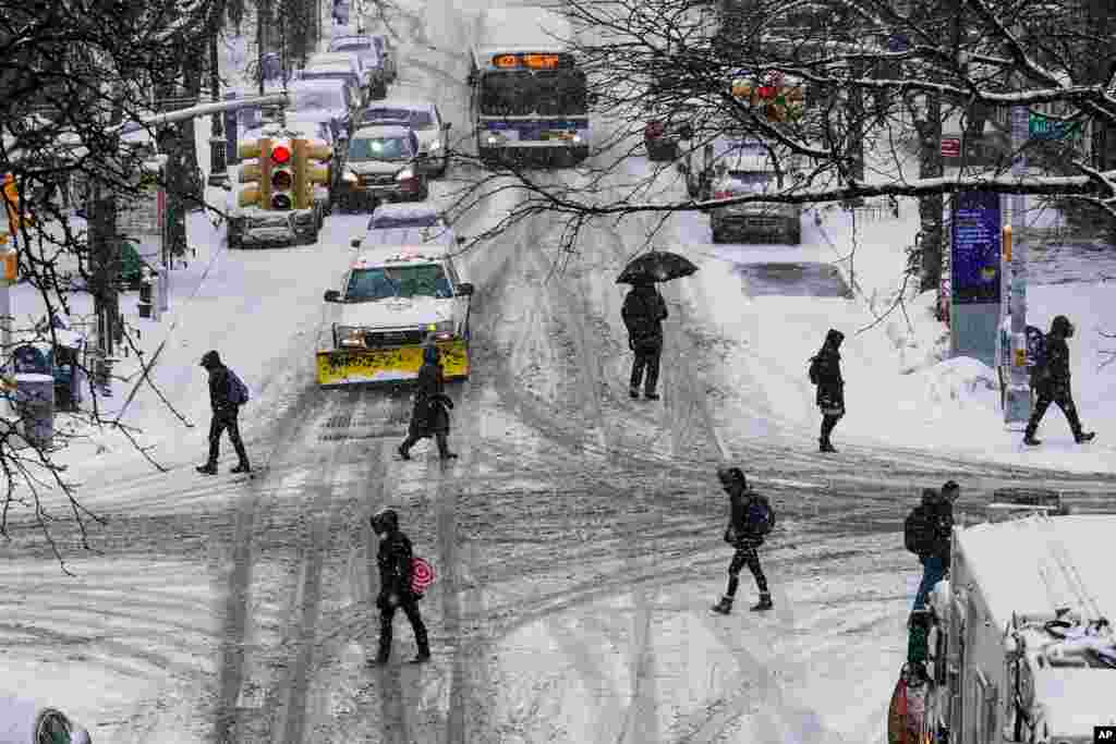 Pedestrians cross 71st Avenue as snow falls in the Queens borough of New York.