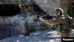 An Israeli soldier shoots rubber bullets at Palestinians during clashes following the death of Palestinian prisoner Khader Adnan during a hunger strike in an Israeli jail, in Hebron in the Israeli-occupied West Bank May 2, 2023. 