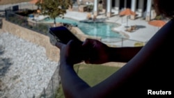 เอเดรียโอนา เพรเทอร์ ถือโทรศัพท์ระหว่างยืนที่ระเบียงในอพาร์ตเมนต์ ที่ดัลลัส รัฐเท็กซัส เมื่อ 5 ส.ค. 2024 (REUTERS/Natalie Thomas)