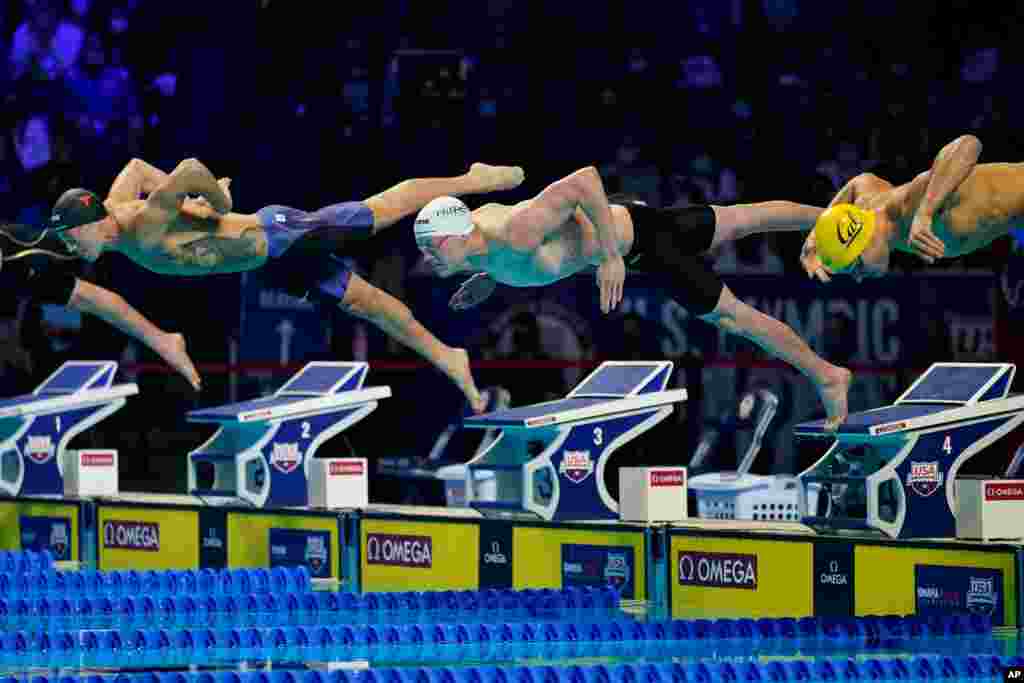 Drew Kibler, left, Patrick Callan, center, and Andrew Seliskar, right, dive at the start of the men&#39;s 100-meter freestyle semifinal during wave 2 of the U.S. Olympic Swim Trials in Omaha, Nebraska, June 14, 2021.