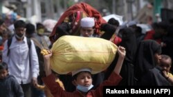 Para pengungsi Rohingya membawa barang-barang mereka meninggalkan kamp pengungsi di Jammu, Minggu, 7 Maret 2021. (Foto: Rakesh Bakshi/AFP)