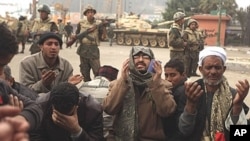 Egyptian anti-government demonstrators and members of the Egyptian Muslim Brotherhood movement pray in front of Egyptian soldiers at Cairo's Tahrir Square, February 7, 2011