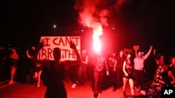 In this May 29, 2020, photo, Portlanders march with flares from the George Floyd vigil at Peninsula Park towards the Justice Center downtown in Portland, Oregon.