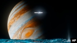 This illustration provided by NASA depicts the Europa Clipper spacecraft above the surface of the moon Europa, foreground, and Jupiter behind. (NASA/JPL-Caltech via AP)