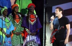 FILE - Singer Johnny Clegg, right, perfoms with the Soweto Gospel Choir at Ellispark stadium in Johannesburg, Dec. 1, 2007.