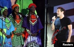 FILE - Singer Johnny Clegg, right, perfoms with the Soweto Gospel Choir at Ellispark stadium in Johannesburg, Dec. 1, 2007.