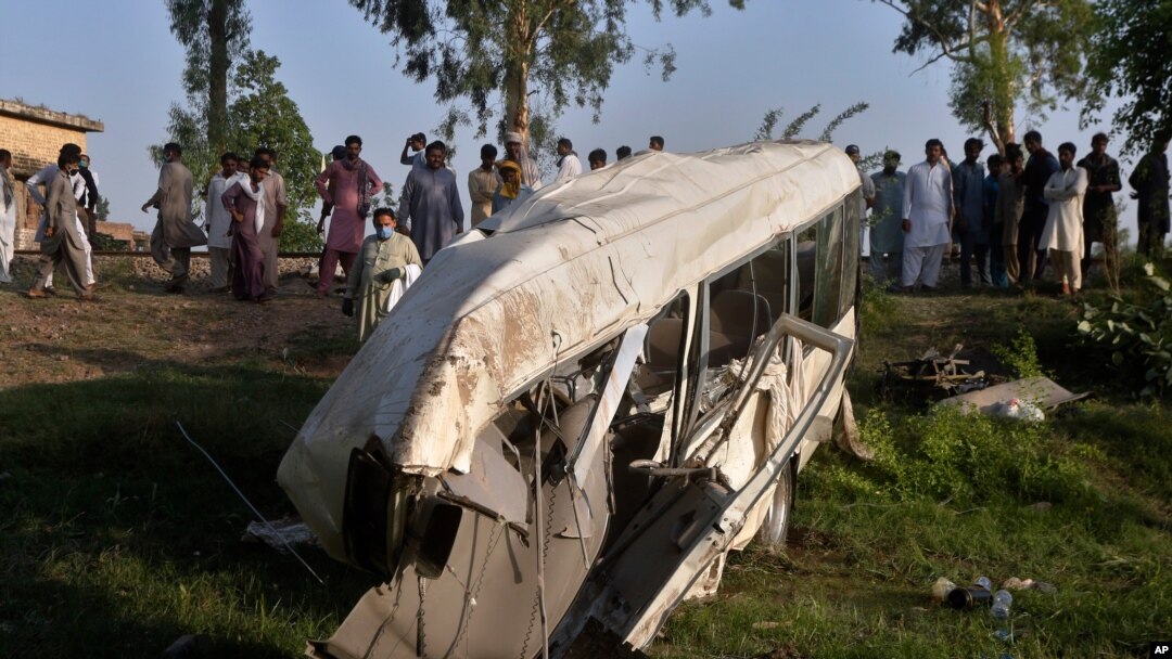 Penduduk setempat berkumpul di sekitar bus yang hancur akibat tabrakan dengan kereta api di Farooq Abad, distrik Sheikhupura, Pakistan, Jumat, 3 Juli 2020. 