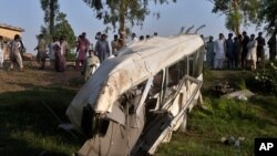 Local residents gather beside the wreckage of a bus close to a railway track following a train and bus accident, in Farooq Abad in Sheikhupura district, Pakistan, July 3, 2020. 