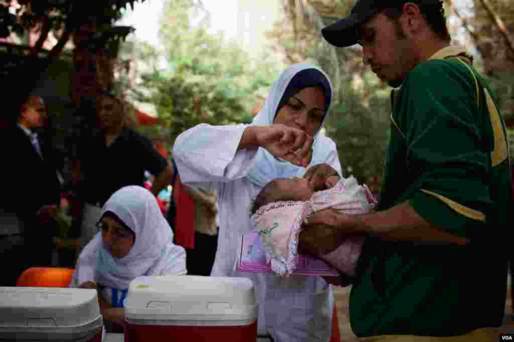 Para orangtua berbaris di Kairo dalam kampanye imunisasi polio di Mesir yang didorong oleh wabah penyakit itu di Suriah (17/11). (VOA/Yuli Weeks)