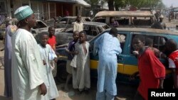 Residents survey vehicles damaged after a bomb blast at a primary school in Maiduguri, the capital of Nigeria's Borno state, February 29, 2012. 