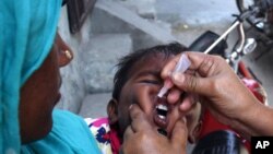 A Pakistani health worker gives a child a polio vaccine in Lahore, Pakistan, Monday, May 5, 2014.