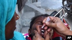 Seorang petugas kesehatan Pakistan memberi seorang anak vaksin polio di Lahore (5/5). (AP/K.M. Chaudary)