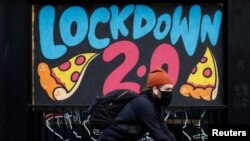 A man cycles past a mural on the boarded up window of a closed pizza restaurant amid the outbreak of the coronavirus disease in Manchester, Britain, Jan. 4, 2021. 