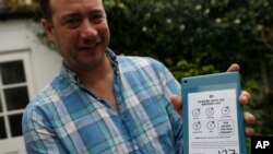 Nicky Woolf shows off an audio device for their project Books for Dad, which he runs with his brother Sam, at, home in London. When their father Geoff Woolf got sick with COVID-19, they turned to e-books to help him, Aug. 15, 2020.