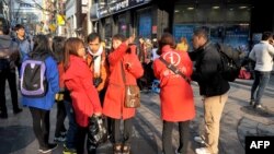 Turis asing bertanya kepada pemandu wisata Korsel berjaket merah, di sebuah jalan di ibukota Seoul, Selasa (9/4).