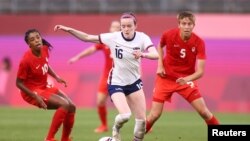 Pertandingan semi final sepak bola putri Tim AS melawan Kanada di stadion Ibaraki Kashima, Jepang, 2 Agustus 2021. Rose Lavelle (AS) diapit Ashley Lawrence (kiri) dan Quinn (kanan). (REUTERS/Edgar Su)